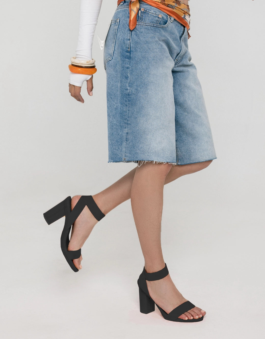 Person wearing denim shorts and black convertible sandals on a plain background