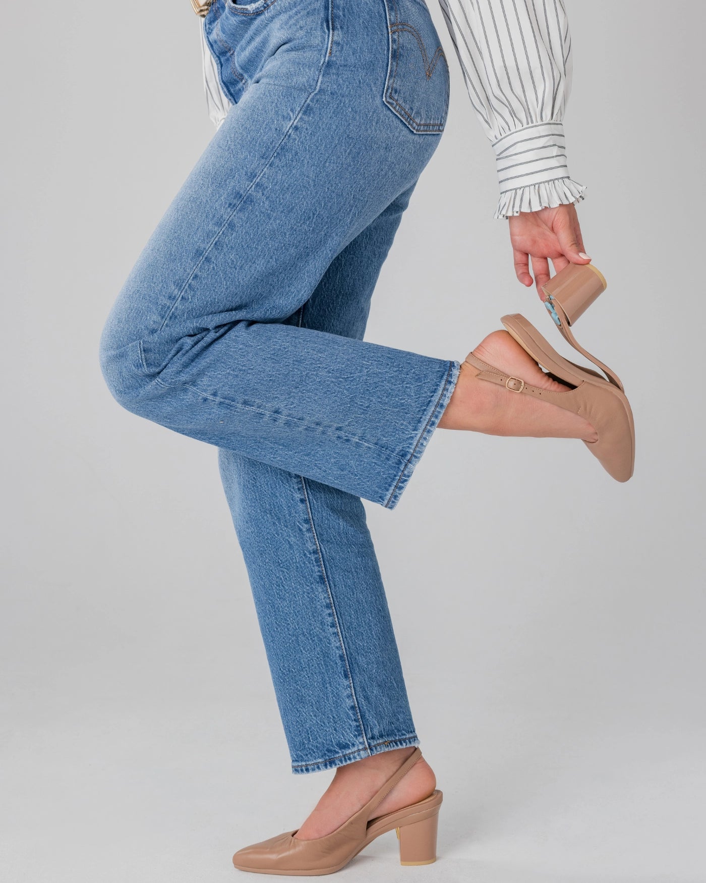 Person wearing blue jeans and tan slingback block heels