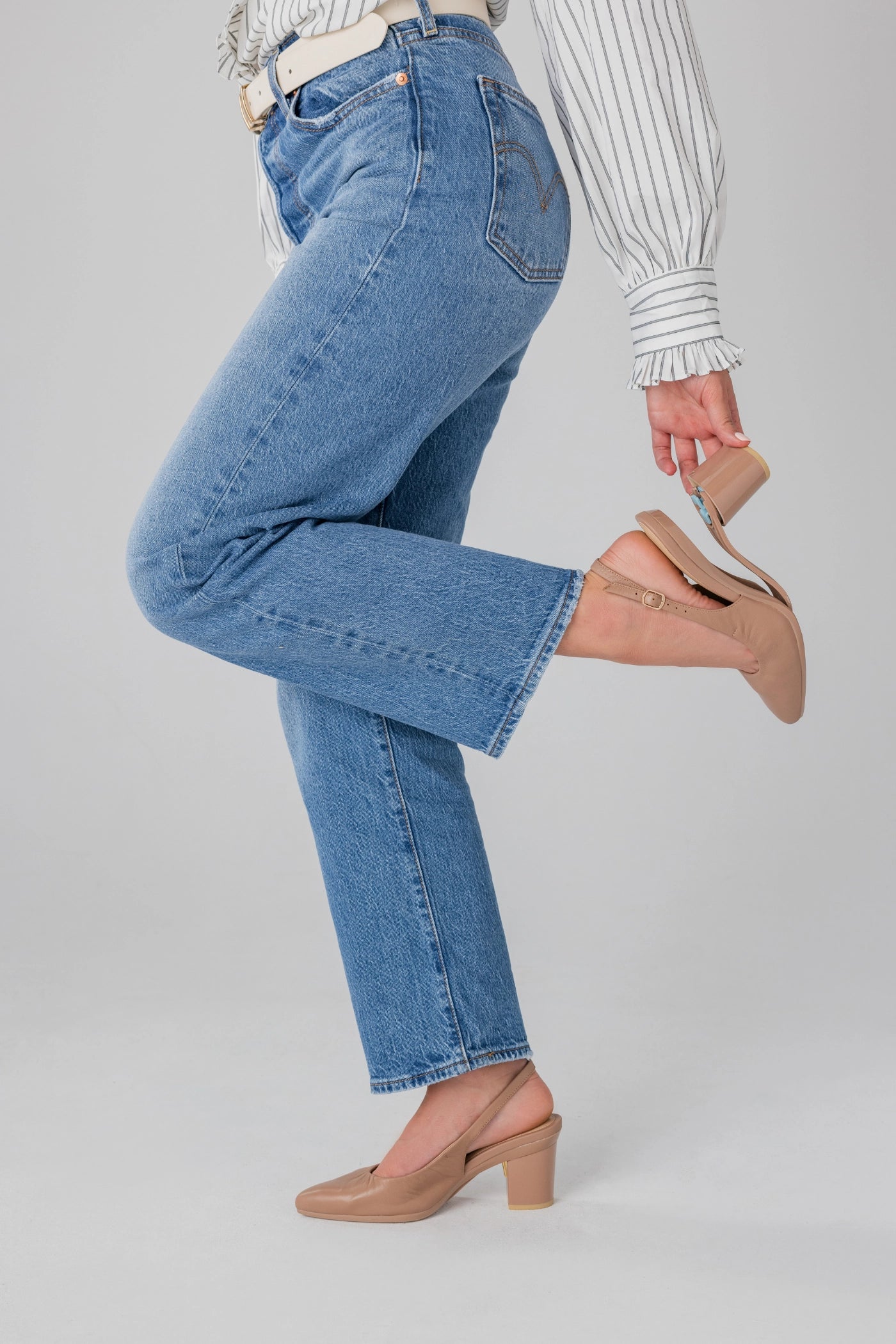 Person wearing blue jeans and tan slingback block heels