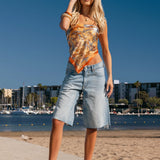 Woman standing on a beach with a clear blue sky and waterfront background