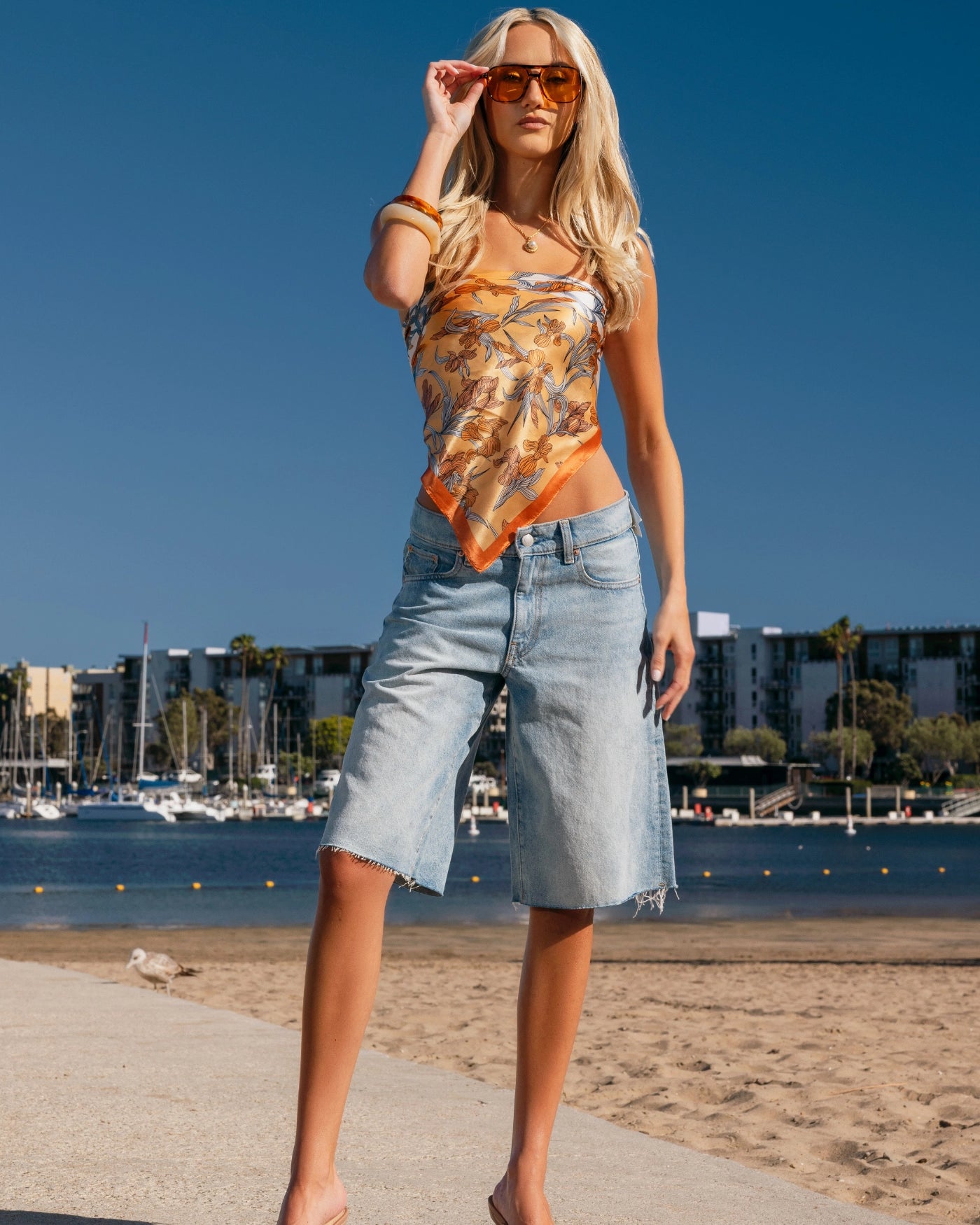 Woman standing on a beach with a clear blue sky and waterfront background